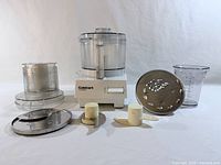 All components laid out including motor base, bowls, blades, discs, measuring cup