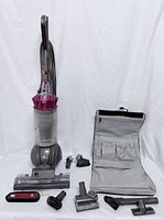 Vacuum with all accessories laid out including tool bag and various heads