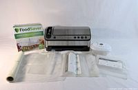 Full lot showing vacuum sealer, marinating canister box, vacuum bag roll, pre-cut bags, round container, manual