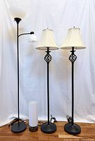 All four lamps lined up: torchiere, two matching traditional floor lamps, cylindrical table lamp