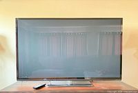 Front view of Panasonic 65-inch plasma TV on stand with remote visible