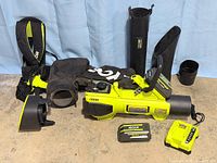Full set laid out: blower body, harness, vacuum bag, batteries, charger, tubes/nozzles