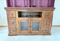 Front view of solid wood media cabinet with open shelf, glass doors, six drawers