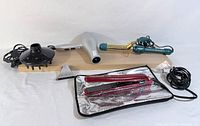 All items laid out: curling iron, straightener on heat mat, hair dryer with diffuser and concentrator cords visible