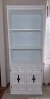 Front view of bookcase showing shelves and closed cupboard doors
