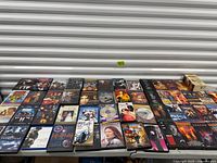 Wide view of first table with rows of DVD cases, loose discs and a few VHS-sized boxes