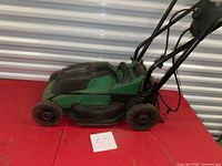 Full view of green Certified electric lawn mower with handle extended