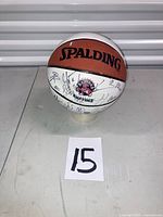 Full view of Spalding two-tone Raptors basketball on stand with lot number card