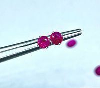 Close view of both ruby studs held by tweezers