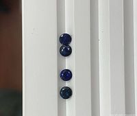 Four round blue sapphires aligned vertically