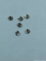 Six loose round brilliant diamonds on flat surface