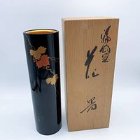 Vase standing beside wooden box showing calligraphy and gold interior