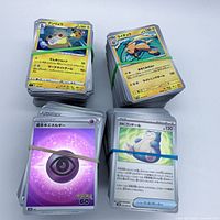 Four stacks of Japanese Pokémon cards bound with rubber bands, visible Raichu and Ampharos cards