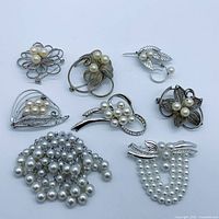 Front view of all eight silver-tone brooches with faux pearls