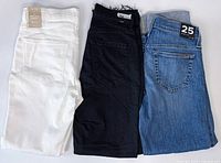 White, black, blue jeans folded side-by-side rear view