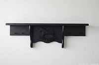 Front view of black wooden shelf coat rack with rocking horse detail
