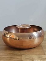 Side perspective of copper bowl showing polished exterior and candle socket