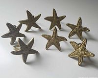 Seven gold-tone starfish napkin rings grouped together on white background