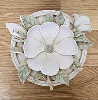 Top view of round ceramic tic tac toe container showing large sculpted flower and leaves