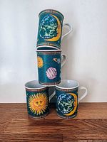 Four ceramic mugs stacked showing celestial graphics