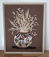 Full view of framed needlepoint showing Navajo-style vase with grain stalks