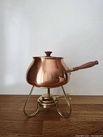 full view of copper fondue pot on brass stand with burner