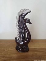 Front three-quarter view of tall brown drip-glazed pottery swan