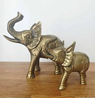 Front three-quarter view of both brass elephant figurines