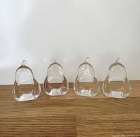 Front view of four clear pear-shaped napkin rings standing upright