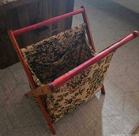 Angled view showing cherry wood X-frame and tapestry fabric pouch interior