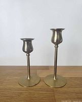 Two brass tulip candlesticks, showing comparative heights and overall design