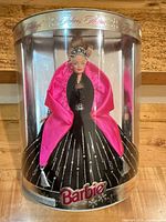 Front view of sealed cylindrical package showing Barbie in black gown with pink wrap