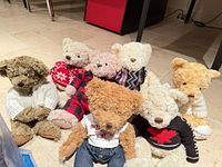 Seven Holt Renfrew bears in various outfits on floor