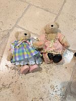 Two Muffy VanderBear plush dolls in distinct outfits lying on floor