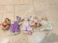 Group view of five North American Bear Co. plush dolls with varied outfits
