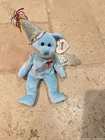 Front view of light blue Ty Beanie Baby March bear with hat and tag