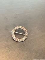 Front view of round silver brooch showing Celtic-style pattern and size