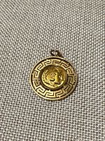 Front view of round 18k gold pendant showing Athena coin and Greek key border