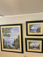 All three framed paintings on wall pegboard