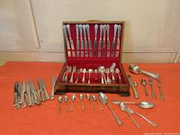 flatware case open with knives in lid, assorted forks and spoons in base, loose pieces arrayed outside case