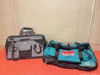 Makita teal/black LXT tool bag and McGuire-Nicholas gray/black tool bag side by side on red surface