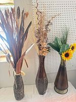 Three artificial plant arrangements in their respective vases