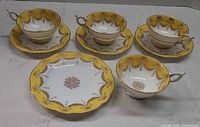 Full view of four teacups, three saucers, one dessert plate