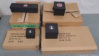 Four cartons labeled 10 pcs each with black jewelry boxes on top, showing both rectangular and square sizes