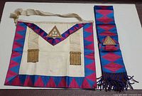Apron and sash laid flat showing full design and colors