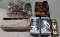 Overview of lot showing chrome rings in bag, wooden and brass rings in box, silver-plated rings boxed, dark wood rings boxed