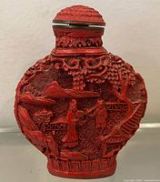 Front view showing carved landscape with two figures, mountains, trees