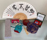Group shot of all items: fan, brocade boxes, pouches, panda trinket, bookmark
