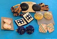 All six pairs of earrings laid out on blue surface