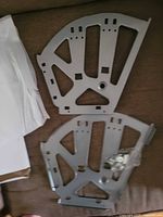 two grey semicircular fold-out shelf hinges with hardware bag